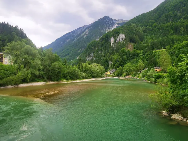 BookNoFees: počitniška nastanitev v Hieflau, Štajerska, Avstrija – Pogled na reko z gozdnatimi gorami in rumeno hišo na bregu