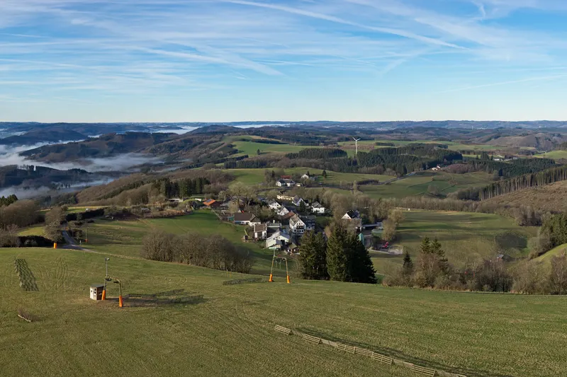 Wildewiese v hribih Sauerlanda, s smučarskim vlečnim napravo na travniku in vasico pod njo